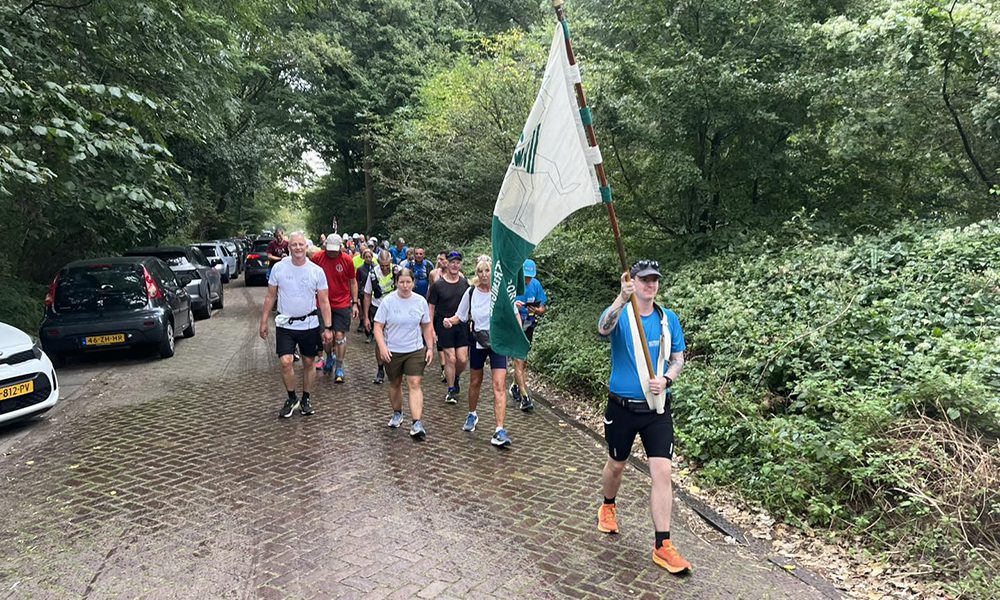 Aankomst wandelaars Nijmegen-Rotterdam met Thomas Leijtens die de vlag draagt. Thomas is de enige deelnemer die in de 21e eeuw is geboren.